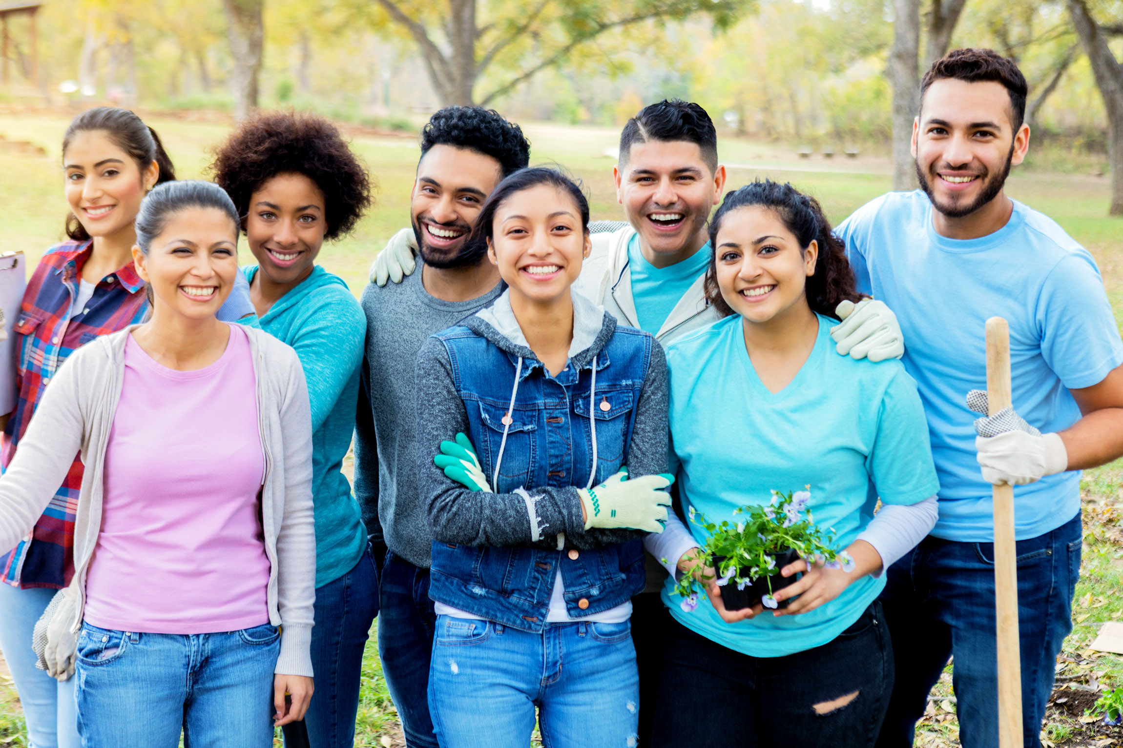 Group of people smiling at the camera taken outside during a gardening project. 