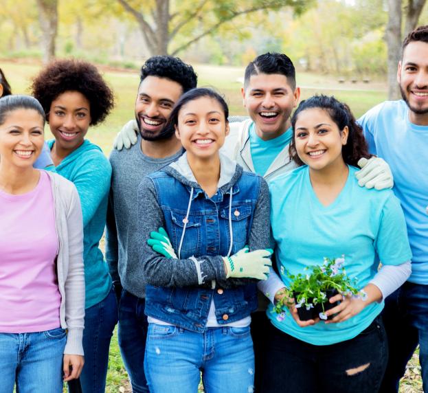 Group of people smiling at the camera taken outside during a gardening project. 